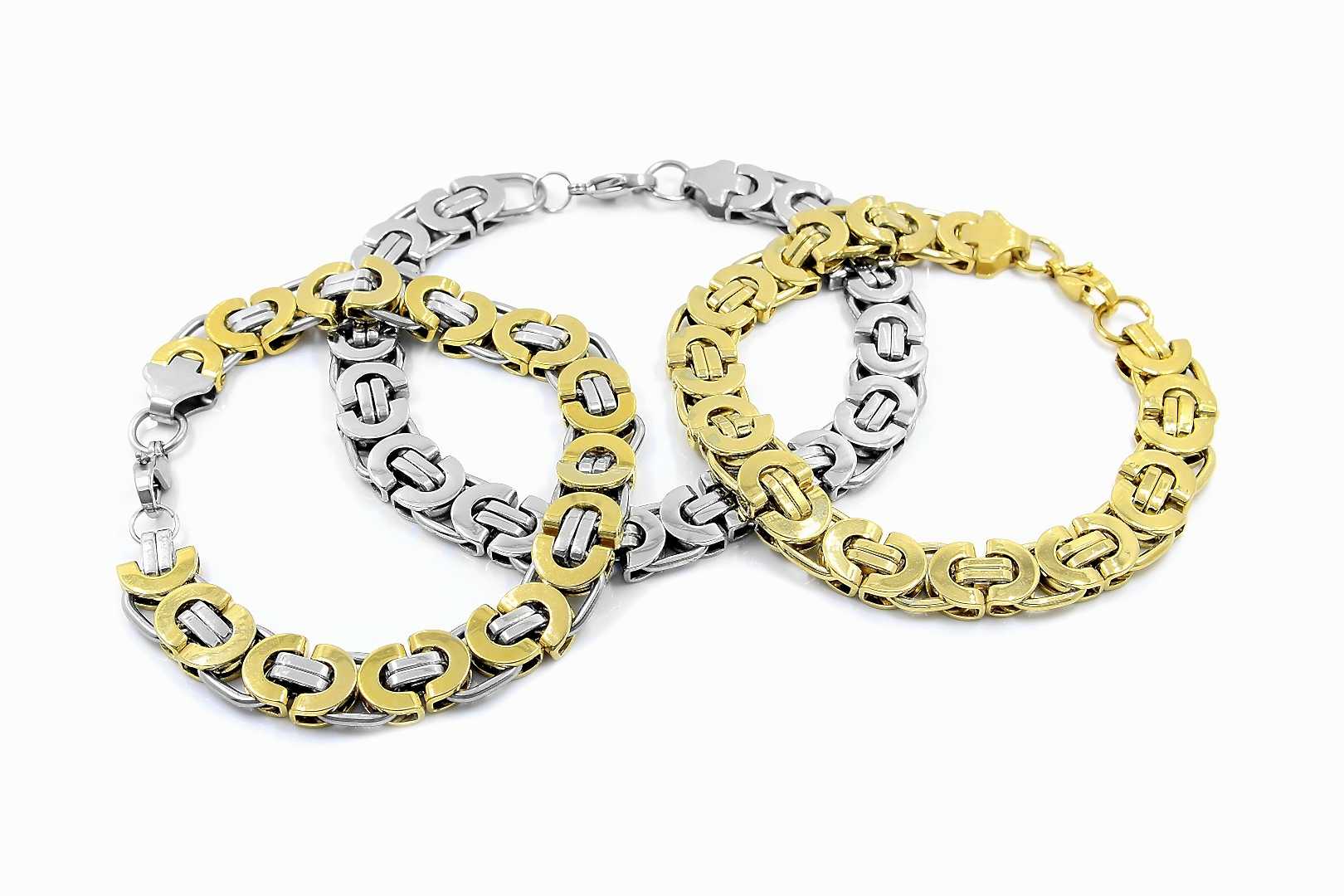 Three gold chain bracelets lay on a white backdrop The one in the middlle is white gold, the one on the right is yellow gold, the one on the left is mixed.