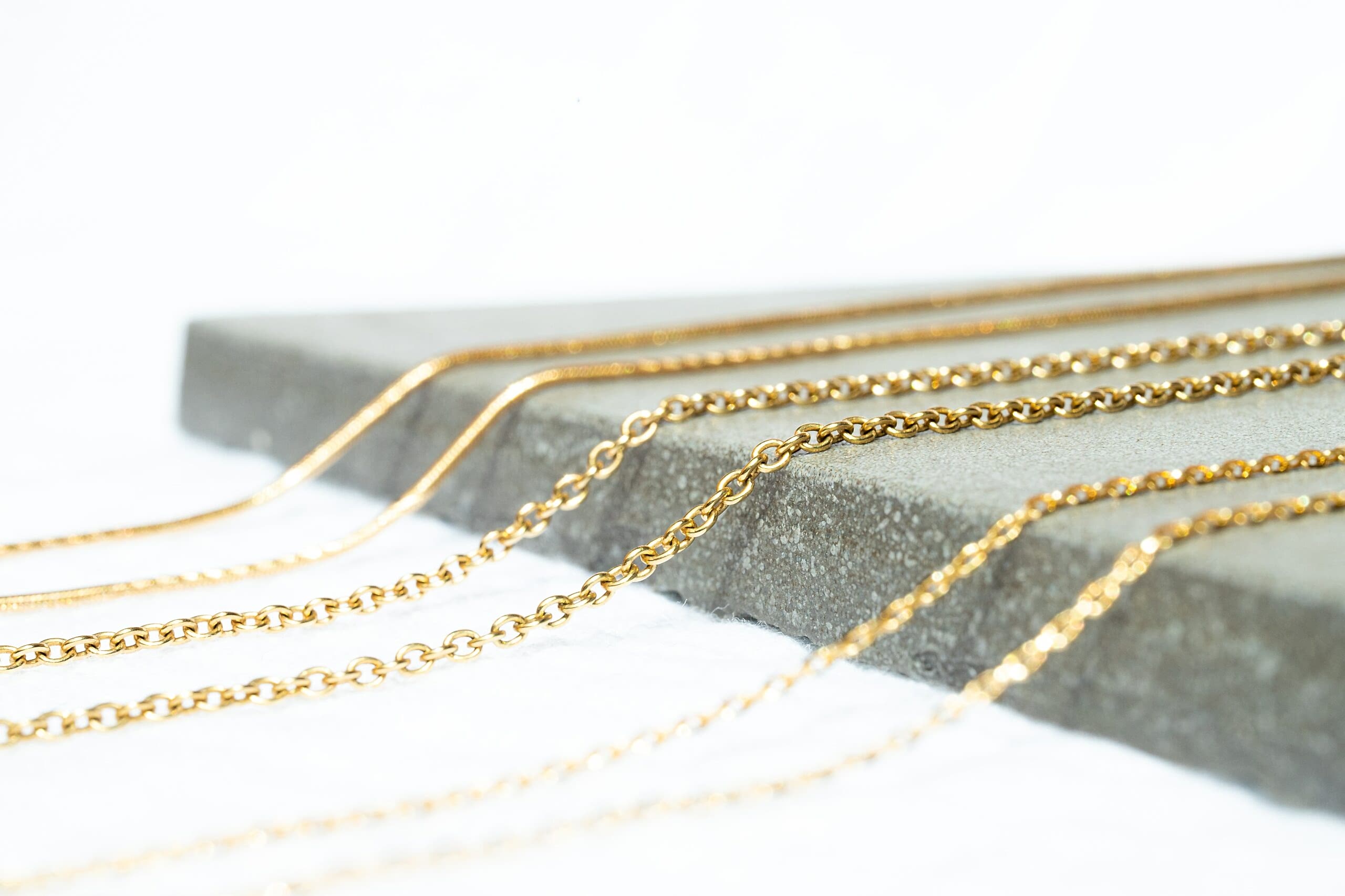 Various textures and sizes of gold chain on display.