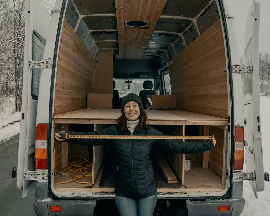 Someone is standing behind a moving van with the back open. They are smiling. The van is empty. Hiring cleaners before move in made it easy to move.