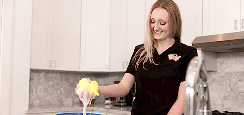 A Naturalcare maid is cleaning a kitchen for some much needed AirBnb cleaning service.