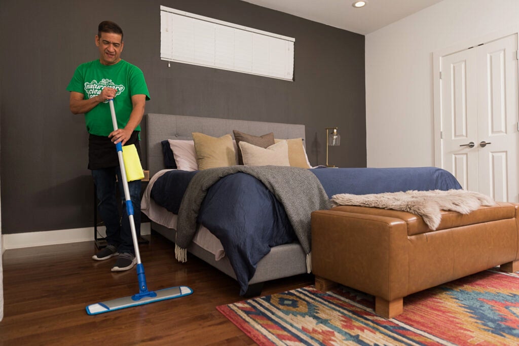 A Naturalcare maid is pre-treating the floors with a microfibre broom before sweeping floors.