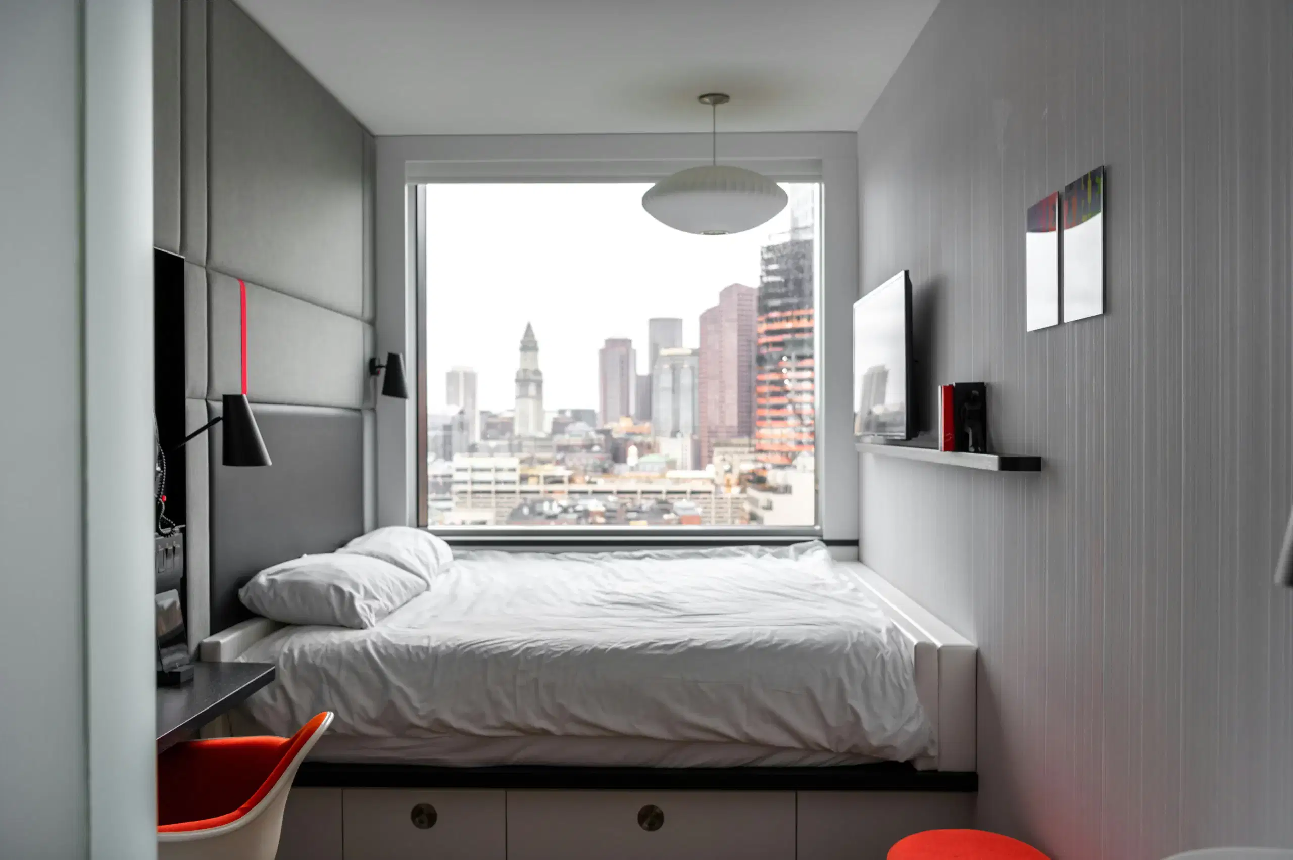 A spotless freshly cleaned Airbnb rental. The bed, in front of a large window, is made crisp.