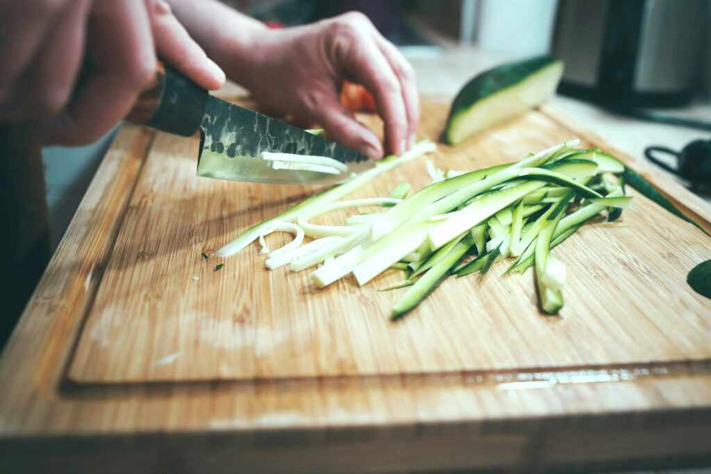 Someone is chopping cucumber on a cutting board. They don't realize there are germs from chicken soaked into the grains of the wood. The cross contamination could kill.