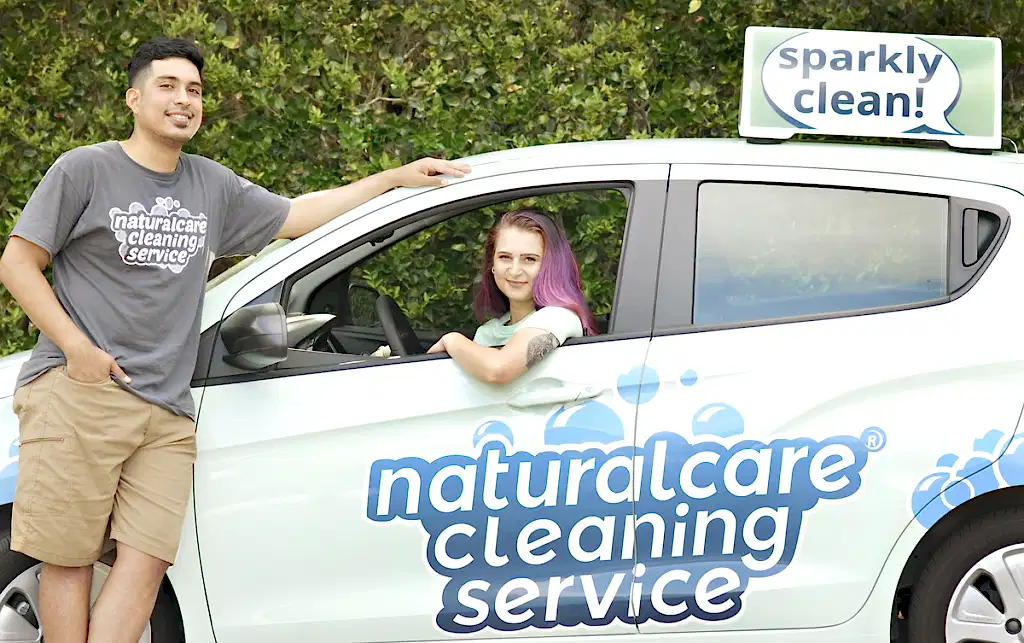 Naturalcare cleaning services maids are talking by a car. One is outside, and one is in the driver's seat. They're the best cleaning services Humble TX can book today.